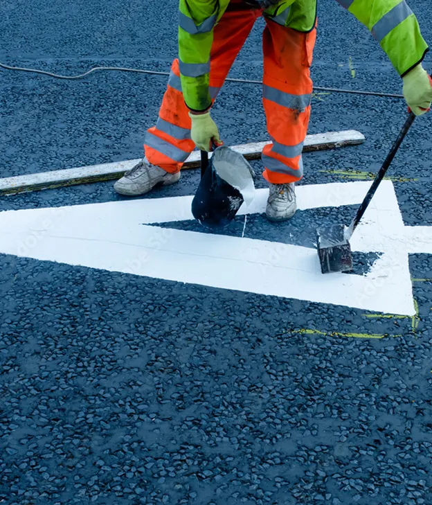 Ouvrier en fluo peignant une flèche blanche sur un revêtement routier foncé à Varennes en Indre-et-Loire 37