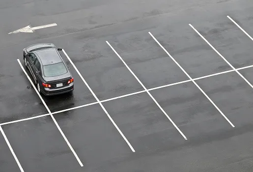 Voiture grise garée sur une place de parking mouillée, flèche de direction au sol à Varennes en Indre-et-Loire 37