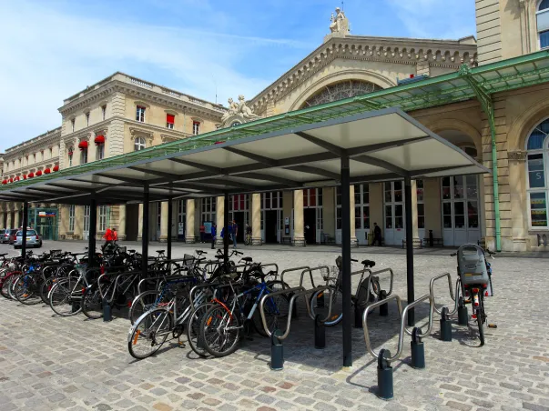 Un parking à vélos couvert devant une gare historique sous un ciel bleu à Varennes en Indre-et-Loire 37
