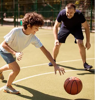 Un père et son fils jouent au basketball sur un terrain extérieur à Varennes en Indre-et-Loire 37