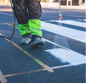 Ouvrier peint des lignes blanches sur l'asphalte noir avec un pistolet à peinture à Varennes en Indre-et-Loire 37