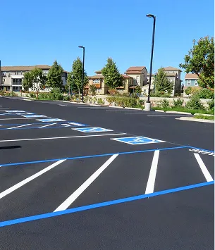 Grand parking vide avec des places bleues et blanches pour les personnes handicapées, sous un ciel bleu clair à Varennes en Indre-et-Loire 37