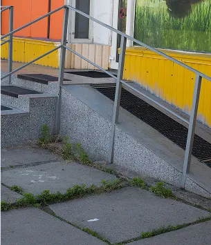 Escalier extérieur en béton gris avec une rampe métallique et de l'herbe poussant entre les dalles à Varennes en Indre-et-Loire 37