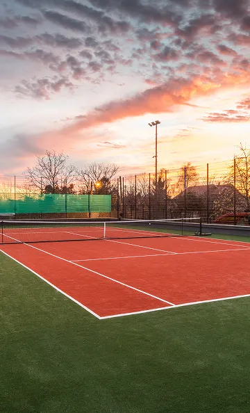 Court de tennis extérieur rouge et vert au coucher du soleil à Varennes en Indre-et-Loire 37