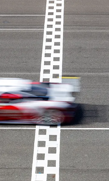 Voiture de course rouge et blanche floue franchissant la ligne d'arrivée à Varennes en Indre-et-Loire 37