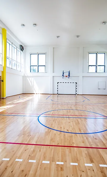 Gymnase intérieur vide avec parquet, lignes de terrain, cerceau de basket et but de futsal à Varennes en Indre-et-Loire 37