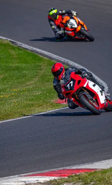 Deux motards en course sur circuit, l'un en rouge, l'autre en orange à Varennes en Indre-et-Loire 37