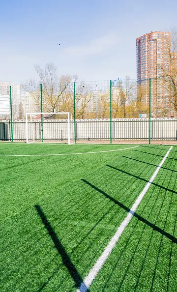 Terrain de football vide en gazon synthétique avec des buts et des bâtiments en arrière-plan à Varennes en Indre-et-Loire 37